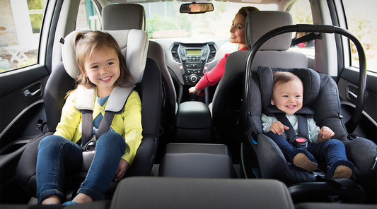 A family driving safely with children securely fastened in their car seats, emphasizing child car safety.